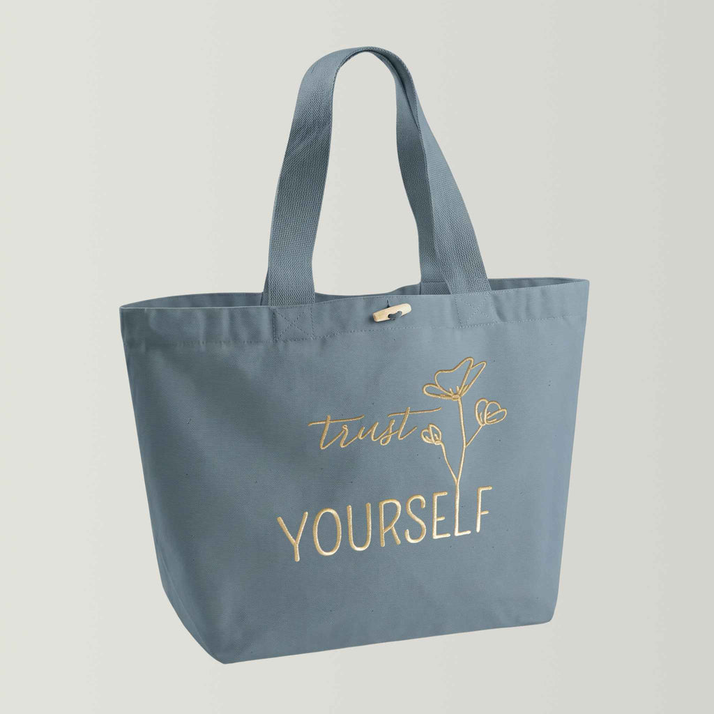 Großer nachhaltiger GOTS-Shopper aus stabilem Canvas (100% Biobaumwolle) mit langen und breiten Henkeln, Farbton hellblau (Dusk blue), große Stickerei in gold-metallic mit Schriftzug Trust yourself