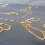 Nahaufnahme einer robusten hellblauen XL GOTS-Tote Bag aus stabilem Canvas (100% Biobaumwolle), mit Fokus auf die edel schimmernde Stickerei in gold-metallic Schriftzug Trust yourself mit minimalistischem floralen Design.
