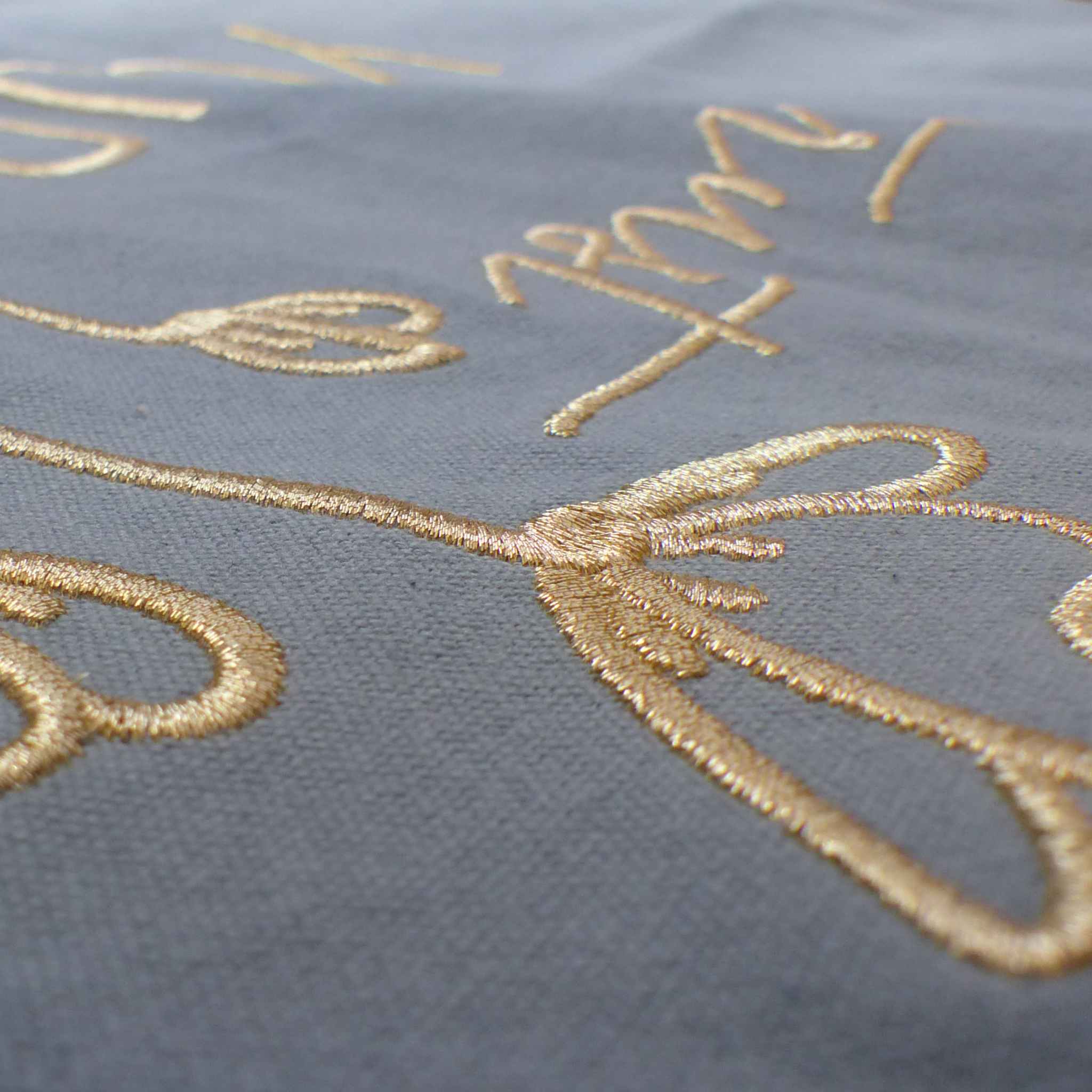 Nahaufnahme einer robusten hellblauen XL GOTS-Tote Bag aus stabilem Canvas (100% Biobaumwolle), mit Fokus auf die edel schimmernde Stickerei in gold-metallic Schriftzug Trust yourself mit minimalistischem floralen Design.