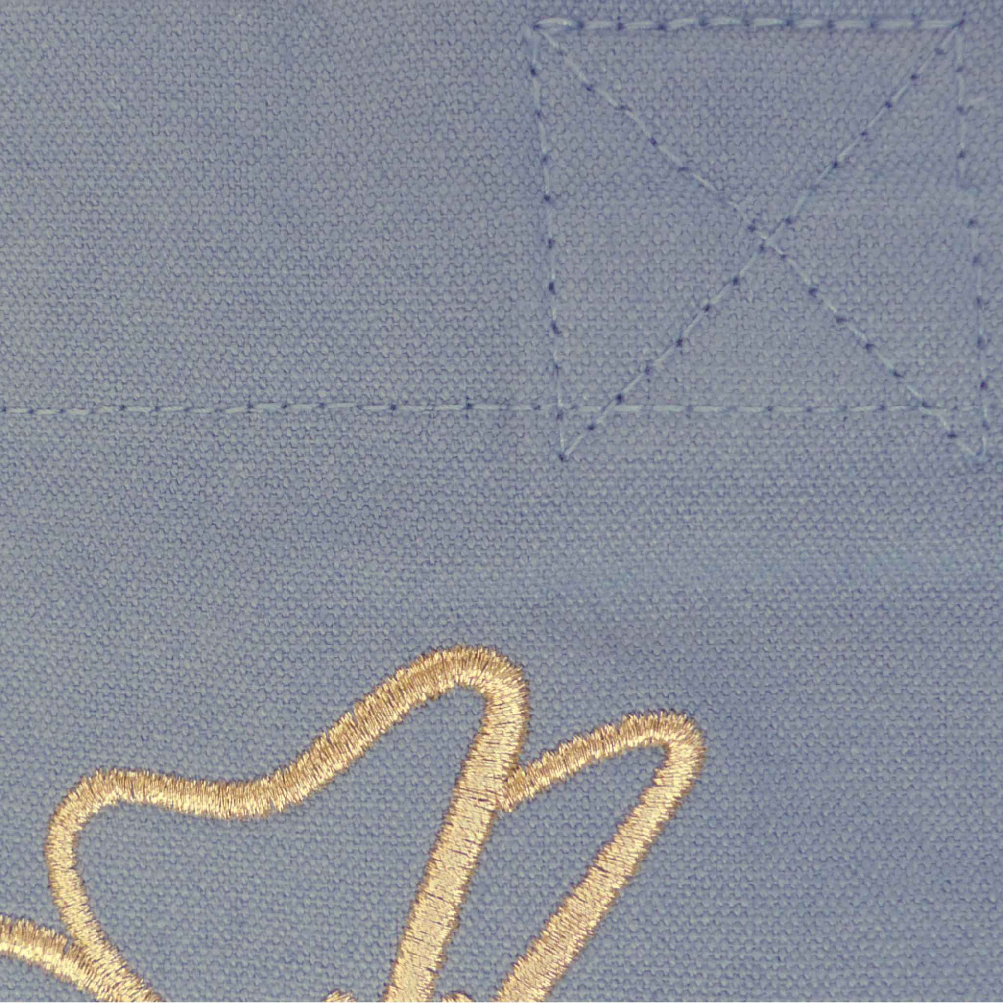 Nahaufnahme einer robusten hellblauen XL GOTS-Tote Bag aus stabilem Canvas (100% Biobaumwolle), mit Fokus auf das minimalistische florale Design welches in gold-metallic gestickt ist