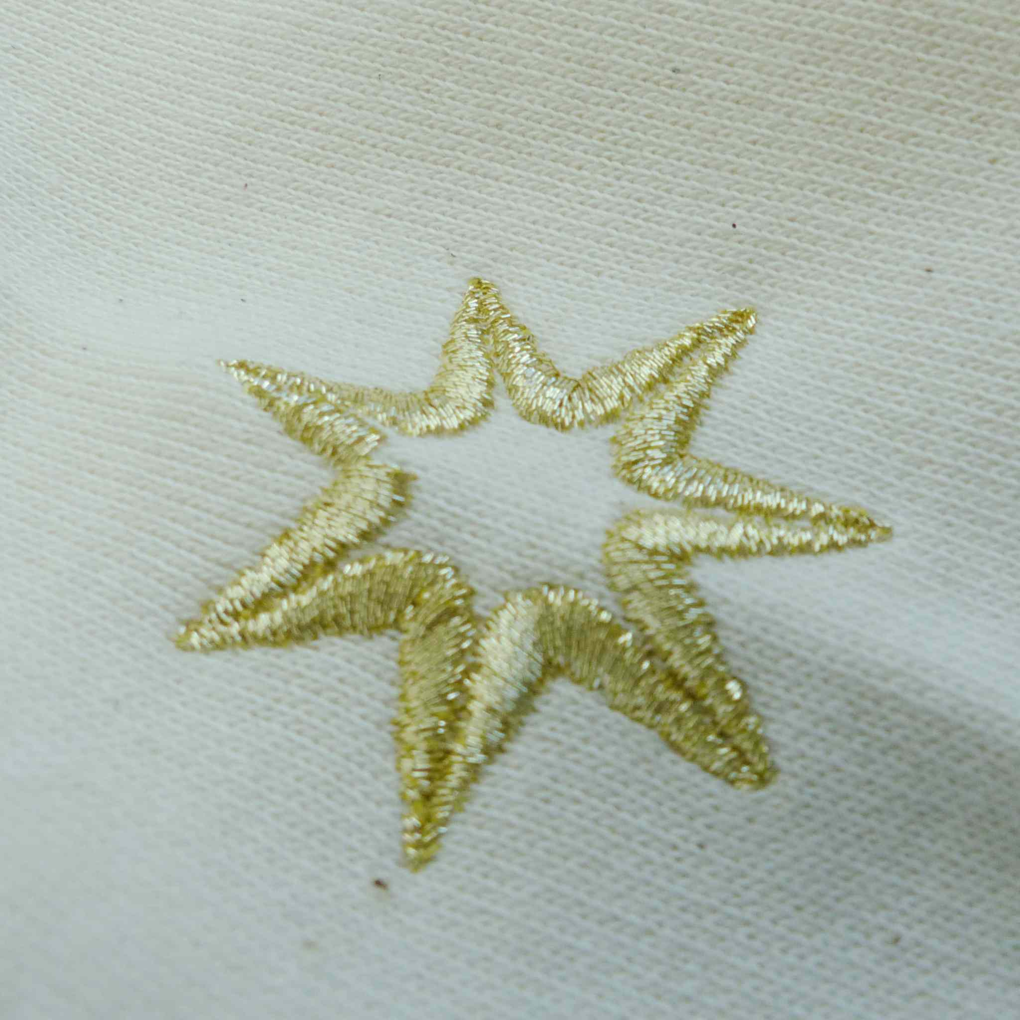 Nahaufnahme der Logostickerei (siebenzackiger Stern) am Ärmel eines nachhaltigen Biodamensweatshirts aus 100% Biobaumwolle im Farbton Natural Raw: Unbehandelte und ungefärbte Biobaumwolle.Logo der spirituellen Bekleidungsmarke Leitstern.