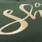 Nahaufnahme einer robusten XL GOTS-Tote Bag aus stabilem Canvas (100% Biobaumwolle), mit Fokus auf die edel schimmernde Stickerei in gold-metallic Schriftzug Time to shine. Farbton Oliv