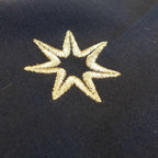 Nahaufnahme der Logostickerei am Ärmel (siebenzackiger Stern) auf einem dunkelblauen Damen T-Shirt aus Bio Baumwolle.