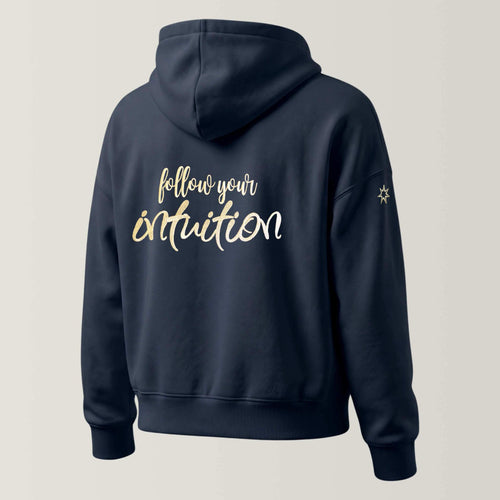 Rückansicht einer dunkelblauen Damen Bio Sweatjacke mit Kapuze der Marke Leitstern. Die Bio Kapuzenjacke zeigt eine große Stickerei am Rücken in metallic-Gold, Schriftzug 'Follow your intuition'. Logostickerei am Ärmel in metallic-gold: siebenzackiger Stern