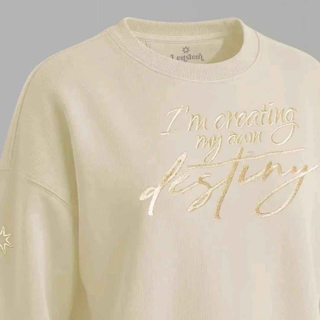 Damen Sweatshirt mit Affirmation (Nahaufnahme). Die Affirmation ist eine große Goldstickerei mit Schriftzug: I'm creating my own destiny. Baumwoll Pullover Damen aus ungefärbter Biobaumwolle