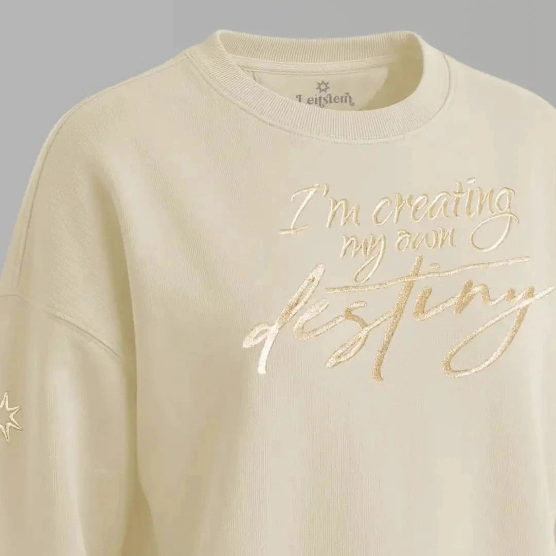 Damen Sweatshirt mit Affirmation (Nahaufnahme). Die Affirmation ist eine große Goldstickerei mit Schriftzug: I'm creating my own destiny. Baumwoll Pullover Damen aus ungefärbter Biobaumwolle