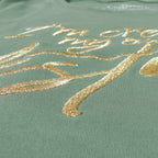 Nahaufnahme eines hellgrünen Bio-Baumwollshirts für Damen aus 100% zertifizierter Biobaumwolle, Fokus auf die große edle Frontstickerei in gold-metallic I'm creating my own destiny