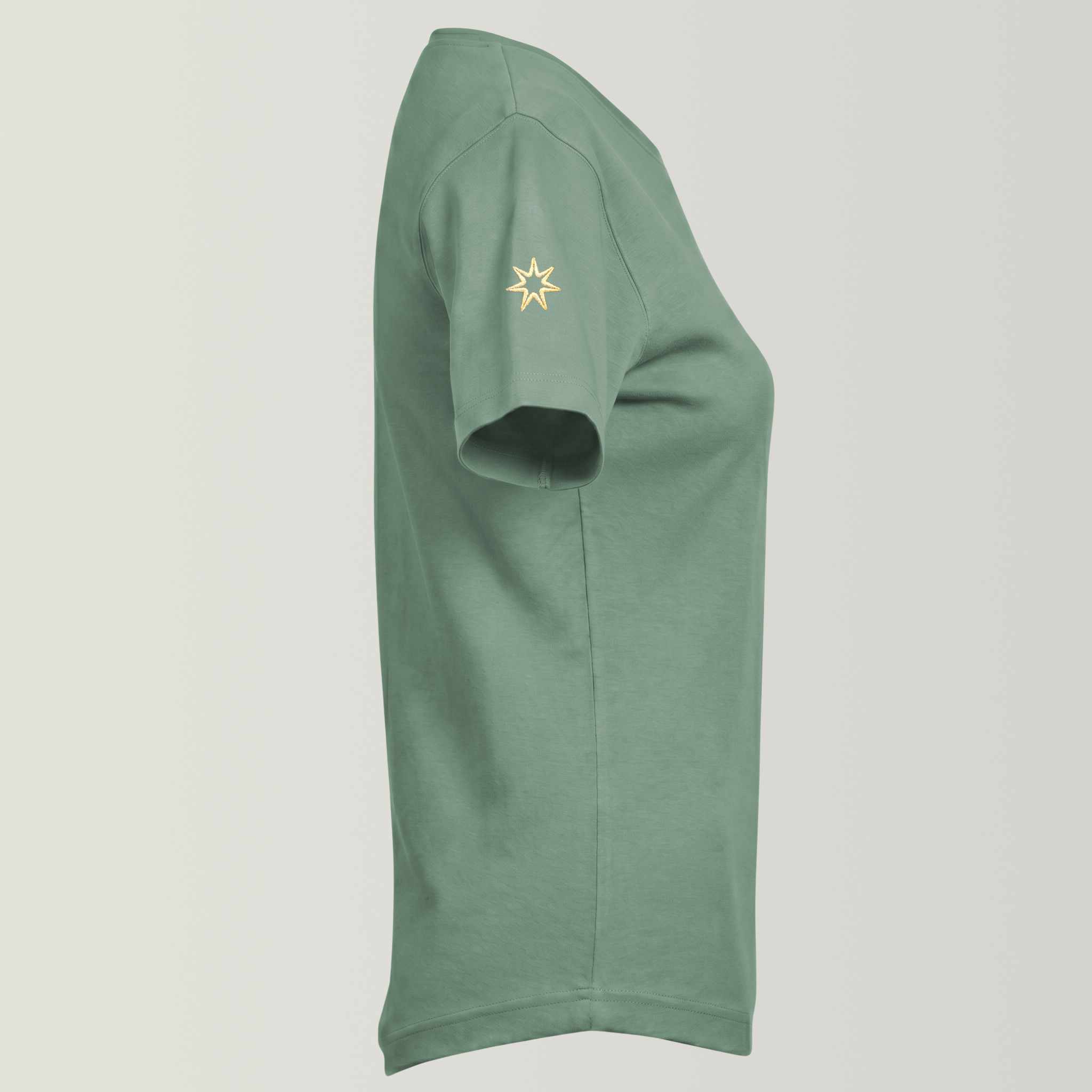 Seitenansicht eines nachhaltigen Damenshirts aus 100% zertifizierter Biobaumwolle in milden Grünton, Logo-Stickerei am rechten Ärmel: siebenzackiger Stern, Symbol der spirituellen Modemarke Leitstern